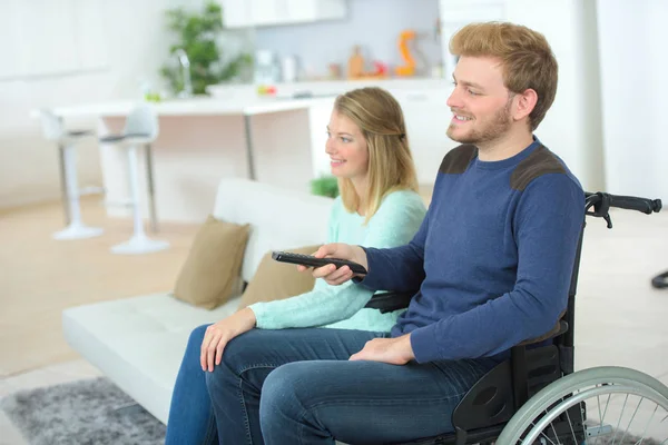 Paar schaut zu Hause fern Mann sitzt im Rollstuhl — Stockfoto