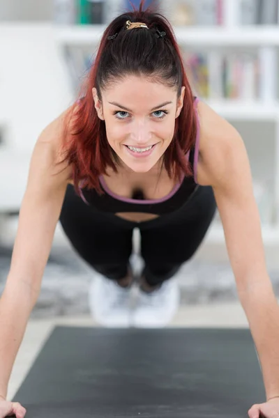 Passar ung kvinna gör en planka i gymmet — Stockfoto