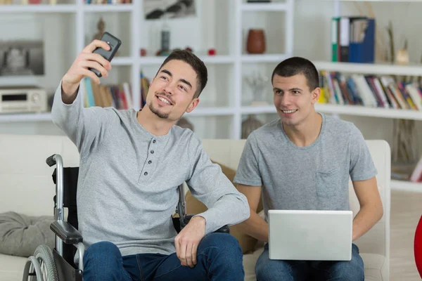 Νεαρός άνδρας λαμβάνοντας μια selfie με τον φίλο του σε αναπηρική καρέκλα — Φωτογραφία Αρχείου