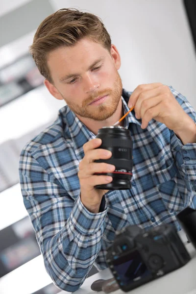 Mann reinigt Linse seiner Digitalkamera mit Spezialpinsel — Stockfoto