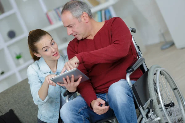 Senior met behulp van een tablet in een rolstoel in thuis — Stockfoto