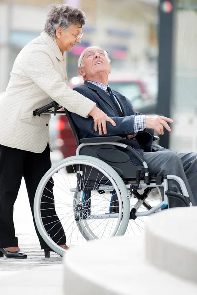 Hombre mayor en silla de ruedas siendo empujado por su esposa —  Fotos de Stock