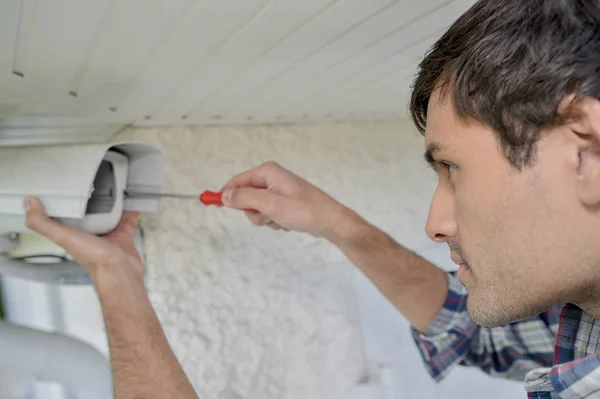 Homme réparant une caméra de surveillance — Photo