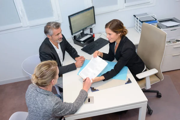 Tre personer i möte runt skrivbord — Stockfoto