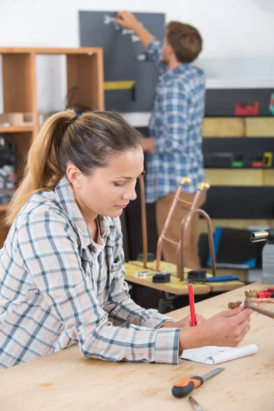 Mladá žena carpenter psaní dokumentu v dílně — Stock fotografie