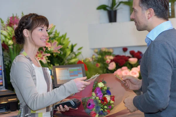 Homme payant fleuriste femme dans la boutique de fleurs — Photo