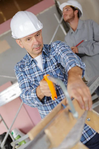 Handyman skära trä med hand såg i garaget — Stockfoto