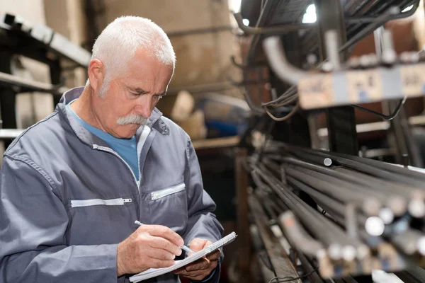 Senior mannen att notera lager av metallstänger — Stockfoto