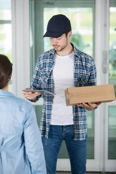 Jovem entregador segurando um papelão — Fotografia de Stock