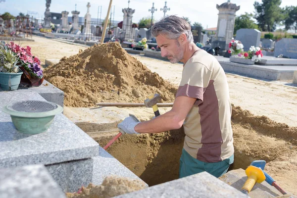 Caucásico hombre cavando tumba en el cementerio — Foto de Stock