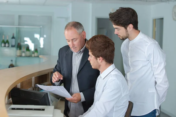 Recepcionistas masculinos localizando no balcão — Fotografia de Stock