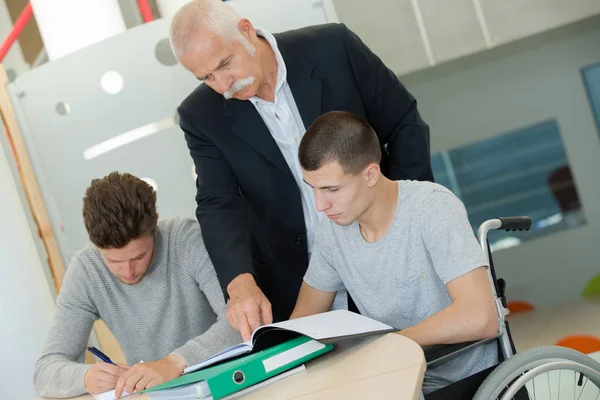 Lehrerin mit zwei Schülern sitzt im Rollstuhl — Stockfoto