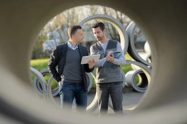 Werknemers naast betonnen rioolbuizen — Stockfoto