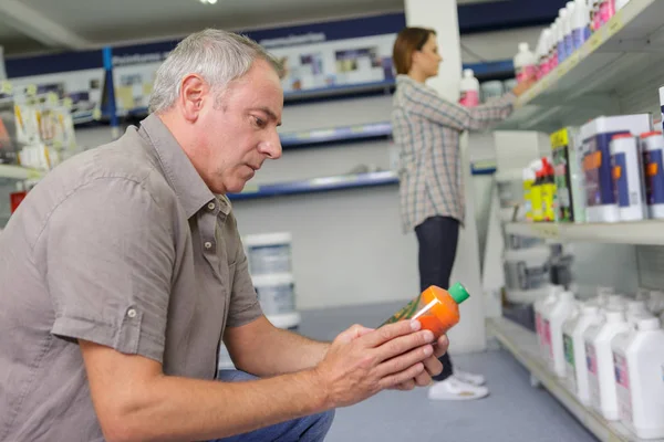 Uomo che sceglie prodotti chimici per la casa nel supermercato — Foto Stock