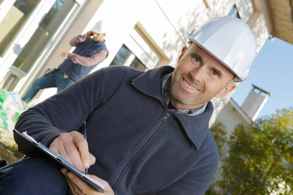 Builder in hardhat with clipboard outdoors — стоковое фото