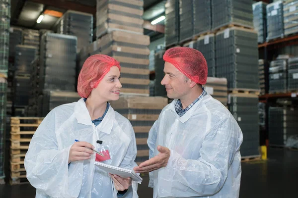 Dois coleagues ocupados olhando para a área de transferência com atribuições — Fotografia de Stock