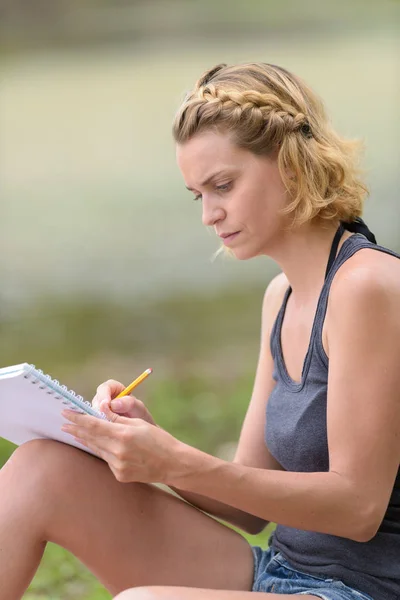 Γυναίκα γράφοντας ένα σημειωματάριο με εξωτερικό — Φωτογραφία Αρχείου