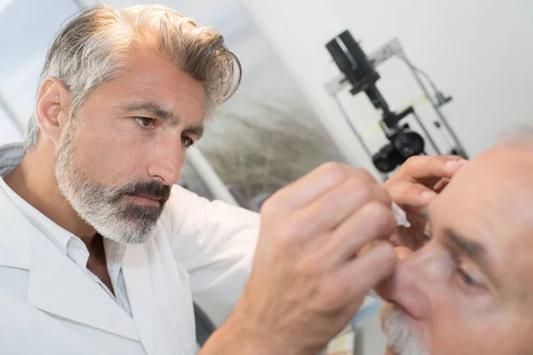 Läkare ögondroppar droppande till patient — Stockfoto
