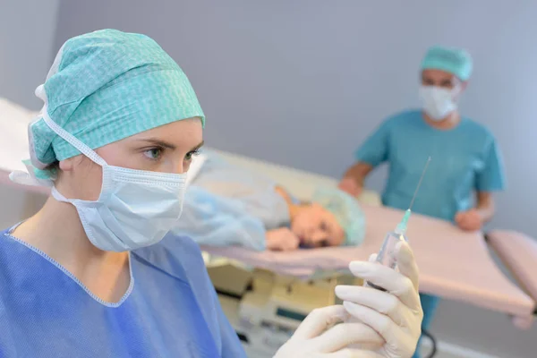 Enfermeira a preparar a injecção para o doente deitado de bruços — Fotografia de Stock