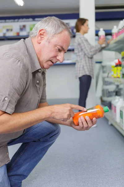 Hombre mayor leyendo la etiqueta en un producto — Foto de Stock