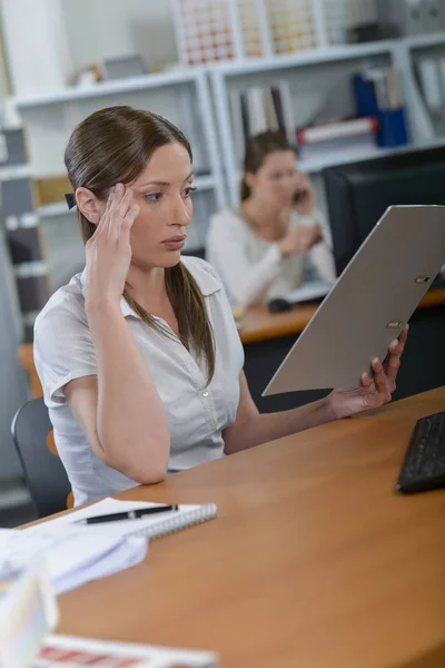 Vrouw leest een documert op haar Bureau — Stockfoto