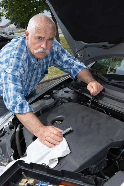 Vieil homme nettoyage moteur de voiture avec microfibre — Photo