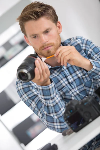 男の小さなブラシでカメラのレンズをクリーニング — ストック写真