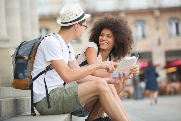 Par av turister consulting en karta över staden — Stockfoto