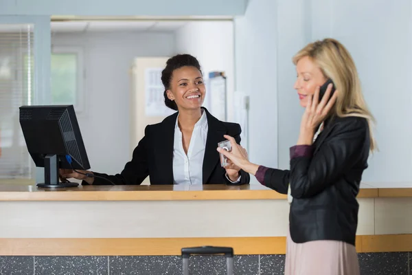 Recepcionista do hotel amigável entregando a chave ao cliente — Fotografia de Stock