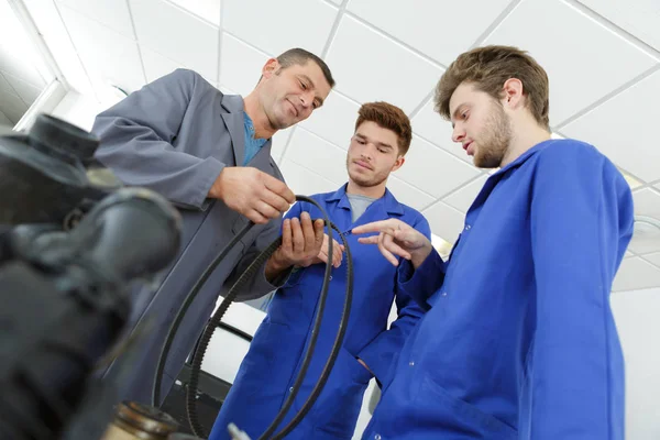 Μαθητευόμενος μηχανικοί στο κατάστημα auto εργάζονται για τον κινητήρα αυτοκινήτου — Φωτογραφία Αρχείου