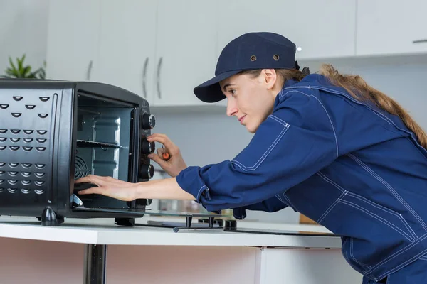 Pracownik naprawy urządzenia piekarnik w pokoju kuchnia — Zdjęcie stockowe