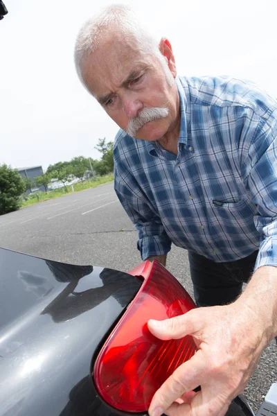 Gammal man installerar bakljus på fordonet — Stockfoto