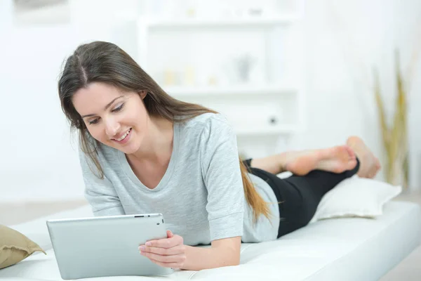 Aantrekkelijke jonge meisje tot op bed holding van een tablet — Stockfoto