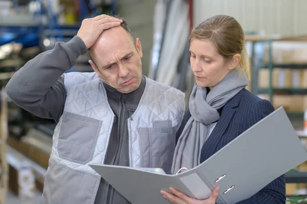 Man frowning while looking at folder held by woman — Stock Photo, Image