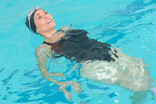 Attraente giovane donna galleggiante in piscina — Foto Stock