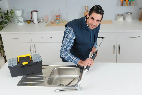 Fontanero usando un tubo de silicona en un fregadero — Foto de Stock