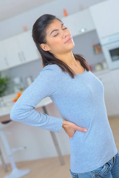 Ung kvinna lider av ryggont hemma — Stockfoto