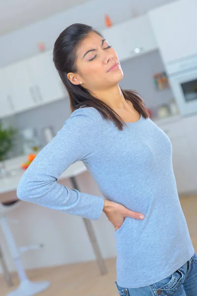 Jonge vrouw die lijden aan rugpijn thuis — Stockfoto