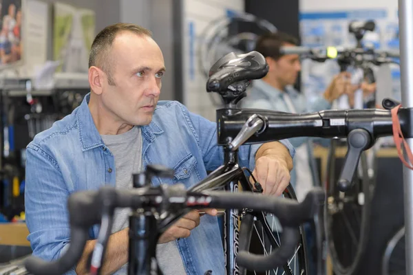 Чоловік перевіряє велосипед перед покупкою в спортивному магазині — стокове фото