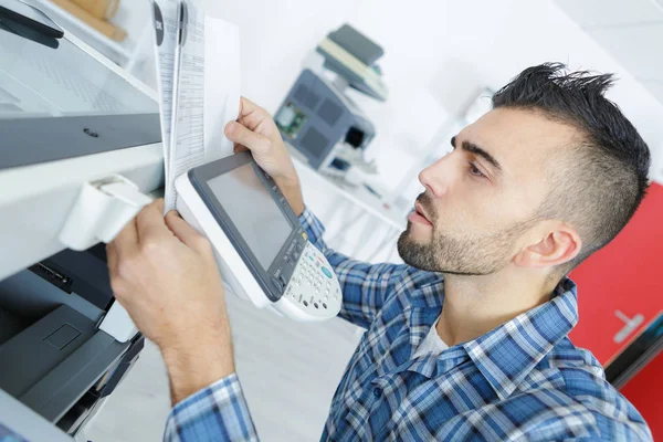 Young man learning to use new printer — Stock Photo, Image