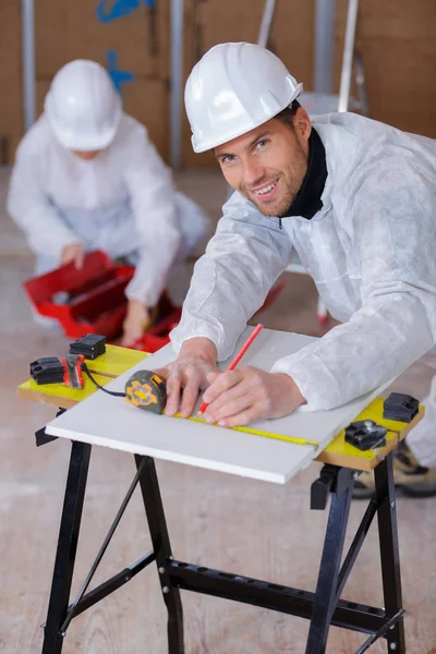 Feliz constructor guapo usando una cinta métrica — Foto de Stock