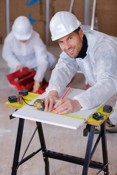 Happy handsome builder using a measure tape — Stock Photo, Image