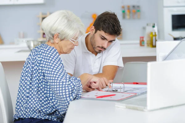 Handsome young lad helping senior lady with her taxes — Stock Photo, Image