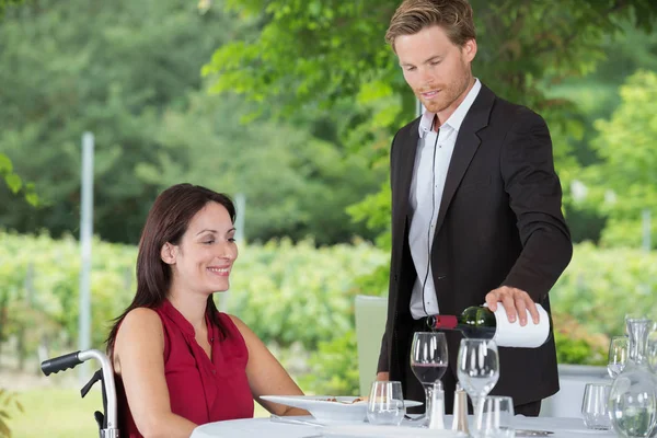 Leuke vrouw in rolstoel eten in een restaurant — Stockfoto