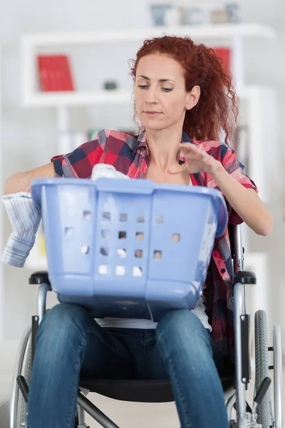 Mujer discapacitada sentada en silla de ruedas lavando su ropa en casa —  Fotos de Stock