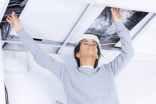 天井に照明を設置する女性電気技師は — ストック写真