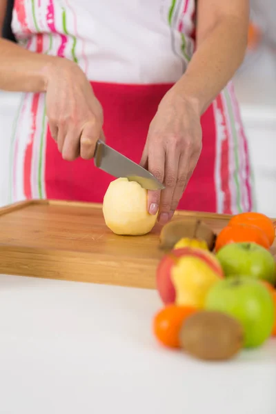 Primer plano en manos femeninas maduras rebanando manzanas en la tabla de cortar —  Fotos de Stock