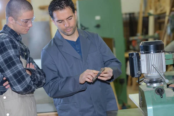 Ingenieur zeigt Lehrling, wie man Bohrer in Fabrik einsetzt — Stockfoto