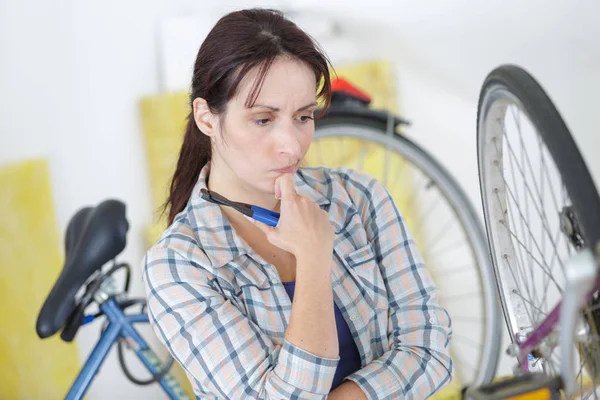 Young woman concentrating on her broken bicycle — Stock Photo, Image