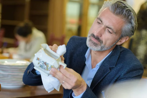 Mature man cleaning china jug — Stock Photo, Image